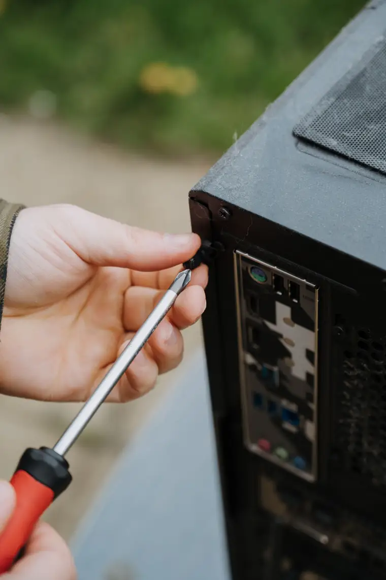 Technician's hands tightening a screw on a desktop computer case