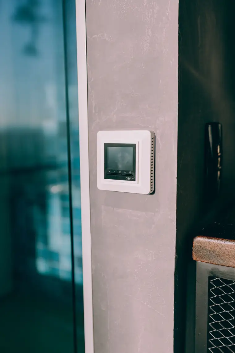Digital thermostat on a wall next to a window