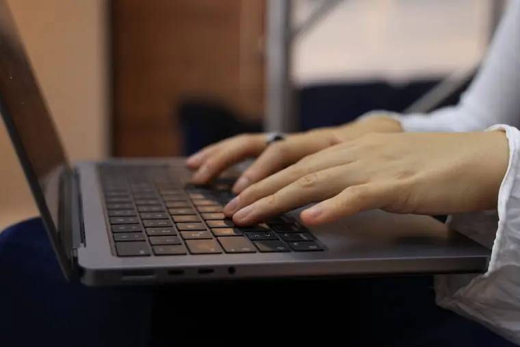 Hands typing on a laptop