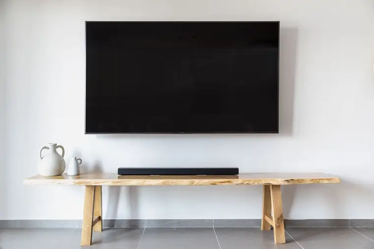 Flat-screen TV mounted on a living room wall above a wooden console and soundbar