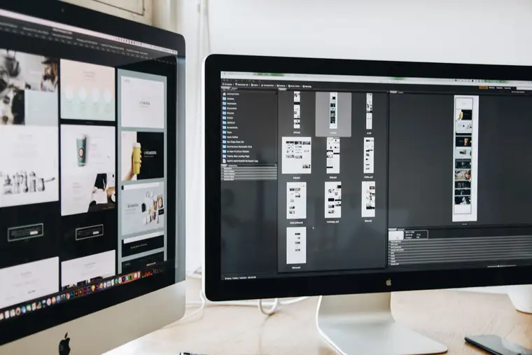 Website design work on two desktop monitors