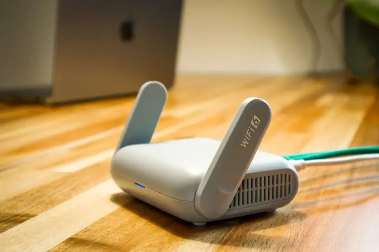Wi-Fi router on a wooden desk with a laptop behind it
